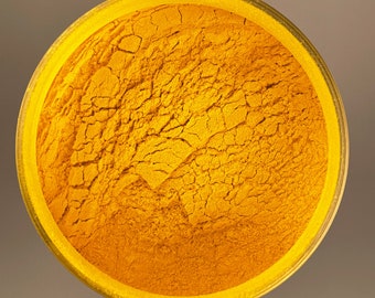 May include: A close-up view of a bowl filled with bright yellow turmeric powder. The powder has a fine, granular texture and is evenly distributed throughout the bowl.