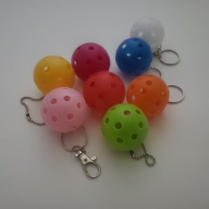 May include: A set of eight colorful, small, plastic balls with holes. Each ball has a silver key chain attached. The balls are red, orange, yellow, green, blue, pink, white, and a darker shade of red.