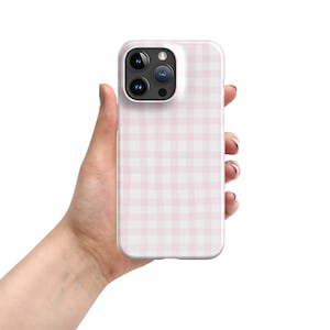 Puede incluir: Una funda de teléfono a cuadros rosa y blanca para un iPhone.