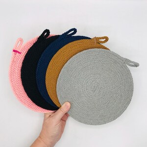 Puede incluir: Cinco posavasos redondos de crochet en rosa, negro, azul marino, marrón y gris. Cada posavasos tiene un asa de bucle.