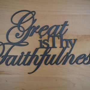 The words Great is Thy Faithfulness are displayed in two different fonts and connected together to hang as a single piece.  Great and Faithfulness are in a highly scripted font with the first letter capitalized.  Other words are in a printed font.