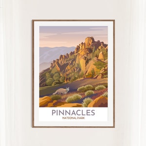 May include: A framed art print showing a stylized landscape of Pinnacles National Park. The artwork depicts a mountain range with a fox, in shades of orange, green, and purple. The text "PINNACLES NATIONAL PARK" is at the bottom.