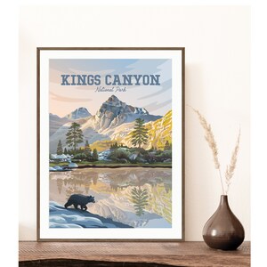 May include: A vintage-style poster with the text "Kings Canyon National Park" in blue lettering. The poster features a scenic view of a mountain lake with a reflection of the mountains in the water. A black bear is walking along the shore of the lake.