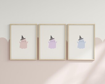 May include: Three framed prints with illustrations of cute ghosts wearing witch hats. The ghosts are in different colors: pink, purple, and blue.