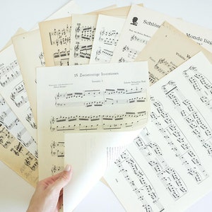 May include: A collection of vintage sheet music with musical notes and titles like "15 Zwölfseitige Inventionen" and "Schlösser in Monde liegen".