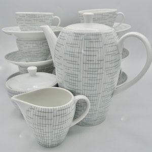 May include: A white tea set with a geometric pattern in grey. The set includes a teapot, creamer, sugar bowl, and four cups and saucers.