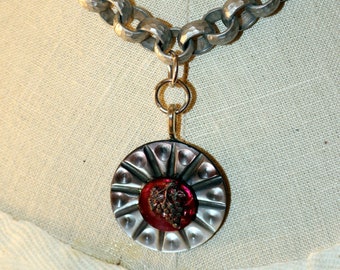May include: A silver chain necklace with a round pendant featuring a grape design in a red glass cabochon.