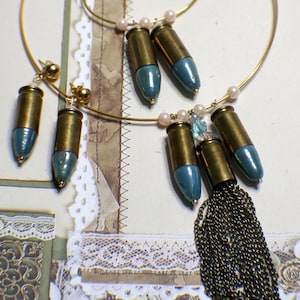 May include: A gold necklace with a chain tassel and bullet-shaped pendants painted in a light blue color. The necklace is paired with matching earrings.