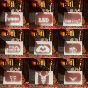 May include: Nine white rectangular signs with various shadow designs and text. The signs display the words "WOOK", "LSD", and "Got kitty?" Other signs show a heart shape, an eye, a deer skull, and the text "I'm here".