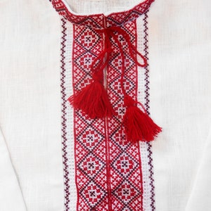 May include: White linen shirt with red and black embroidered details. The embroidery features a geometric pattern with tassels.