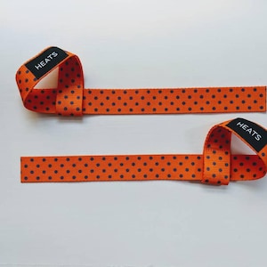 May include: Two orange wrist straps with black polka dots and the word "HEATS" printed on each strap.