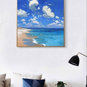 May include: A framed painting depicts a serene beach scene. The artwork showcases a vibrant blue sky dotted with fluffy white clouds. Turquoise water meets a sandy shore, creating a calming coastal landscape.