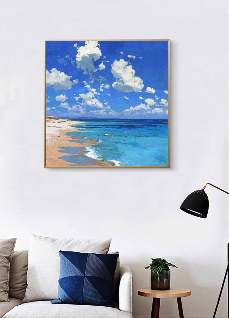 May include: A framed painting depicts a serene beach scene. The artwork showcases a vibrant blue sky dotted with fluffy white clouds. Turquoise water meets a sandy shore, creating a calming coastal landscape.