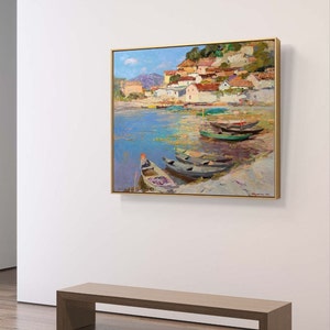 May include: A painting of a small village on a hillside overlooking a body of water with several boats docked. The water is a light blue color and the sky is a bright blue with white clouds. The village is painted in shades of pink, yellow, and brown.