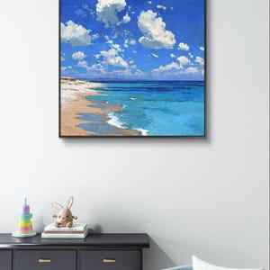 May include: Square framed painting of a beach scene. The artwork depicts a bright blue sky filled with fluffy white clouds. The ocean transitions from turquoise to deep blue, meeting a sandy beach.