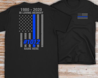 May include: Black t-shirt with a blue line American flag design on the back. The flag has the text "1980 - 2020 IN LOVING MEMORY #1012 NAME HERE". The front of the shirt has a small blue line American flag design on the chest.