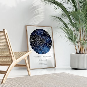 a starry night sky poster with the text "Your first night sky" and "Nathaniel" written on it, placed on a white wall next to a potted plant.