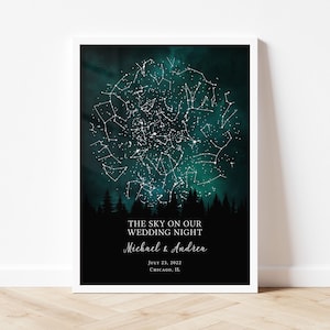 May include: A framed vertical poster featuring a dark teal and black night sky filled with white star constellations above a silhouette of pine trees. The text reads: THE SKY ON OUR WEDDING NIGHT, Michael & Andrea, JULY 23, 2022, CHICAGO, IL.