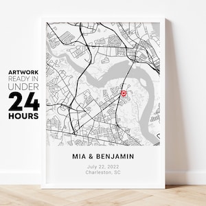 May include: Framed black and white map print showing a detailed street layout with a red heart-shaped marker. The print includes the names "MIA & BENJAMIN", the date "July 22, 2022", and the location "Charleston, SC". Text on the left says "ARTWORK READY IN UNDER 24 HOURS".