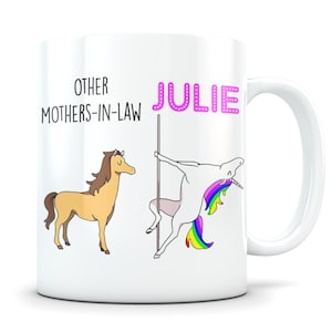 May include: White ceramic mug with a pink unicorn and the text "OTHER MOTHERS-IN-LAW JULIE" printed on it. The unicorn is holding onto a pole and has a rainbow tail. A brown horse is on the left side of the mug.