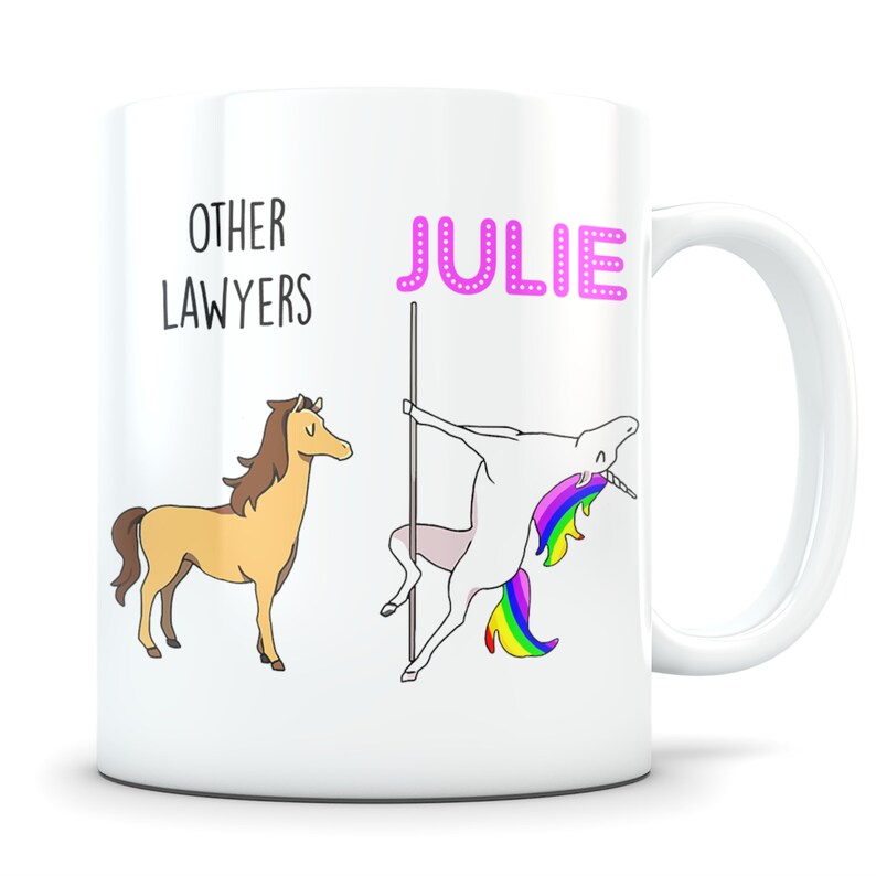 May include: White ceramic mug with a graphic of a unicorn and a horse. The unicorn is pink and has a rainbow tail. The horse is brown. The text "OTHER LAWYERS" is above the horse and the text "JULIE" is above the unicorn.