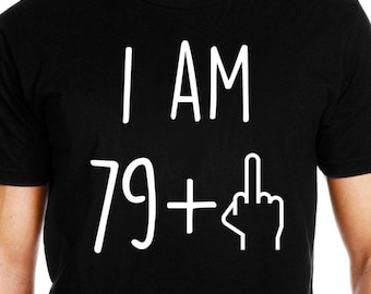 May include: Black t-shirt with white text that reads "I AM 79 +" followed by a white middle finger graphic.