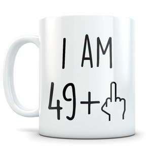 May include: White ceramic coffee mug with black text that reads "I AM 49+  " with a middle finger emoji.