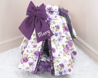 May include: Purple and white floral car seat cover with a large purple bow and the name "Mary" embroidered on it.