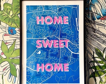 May include: A framed print with a blue map background and the text "HOME SWEET HOME" in pink.