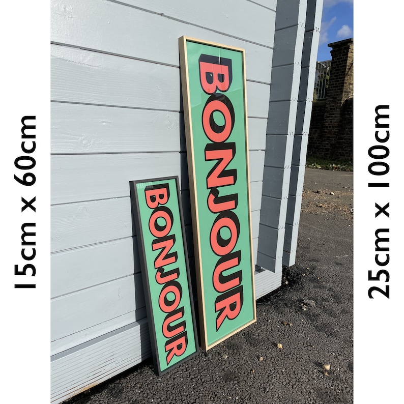 Puede incluir: Dos impresiones enmarcadas con la palabra "Bonjour" en letras grandes, negritas y rosas sobre un fondo verde azulado. La impresi&oacute;n m&aacute;s grande mide 63,5 cm por 254 cm y la m&aacute;s peque&ntilde;a mide 38,1 cm por 152,4 cm.