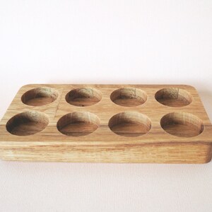 May include: A wooden tray with eight round depressions, perfect for storing small items like essential oils or jewelry.