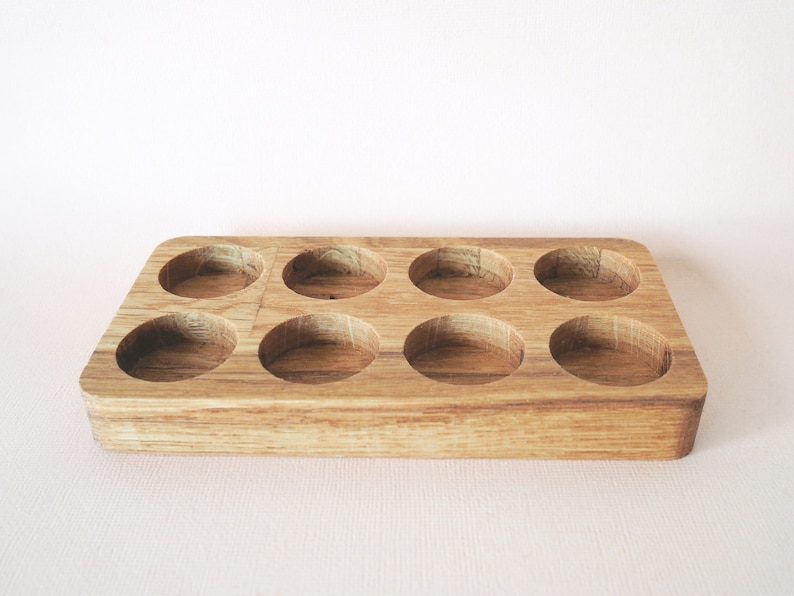 May include: A wooden tray with eight round depressions, perfect for storing small items like essential oils or jewelry.
