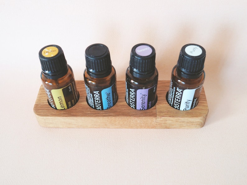 May include: Wooden essential oil holder with four amber glass bottles labeled "Lemon", "Breathe", "Serenity", and "Purity".