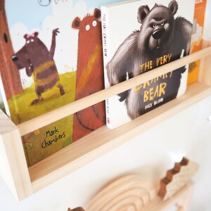 May include: A wooden shelf with two children's books. The book on the left is titled "The Cranky Bear" by Mark Chambers. The book on the right is titled "The Very Cranky Bear" by Nick Bland.