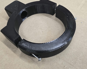 May include: A black, 3D-printed circular clamp with a segmented design. The clamp has angular extensions and is held together with metal screws. The object is designed for mechanical or industrial use.