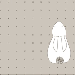 May include: A white bunny illustration with a fluffy tail, set against a light brown background dotted with small 'X' marks. The bunny is viewed from above, with its ears and body clearly outlined.