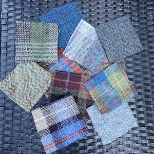 Puede incluir: Surtido de muestras de tela en varios patrones y colores, incluyendo verde, azul, rojo y gris. Las muestras están hechas de tweed y tienen una textura tejida.