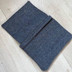 Könnte beinhalten: Eine blaue und graue Tweed-Tasche mit Reißverschluss und Fischgrätenmuster.