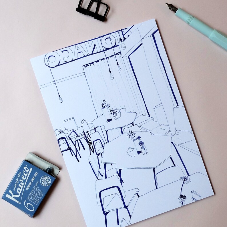 May include: A black and white line drawing of a cafe interior with tables and chairs. The cafe has a large window and a sign that says "Oganik".