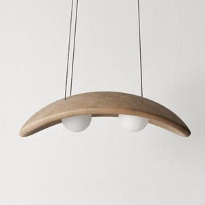 May include: A wooden pendant light fixture with two white globe-shaped light bulbs. The fixture is shaped like a crescent moon.