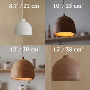 May include: Four pendant lights in different sizes and colors are displayed. The sizes are 8.7' / 22 cm, 10' / 25 cm, 12' / 30 cm, and 15' / 38 cm. The lights are white, brown, and tan.