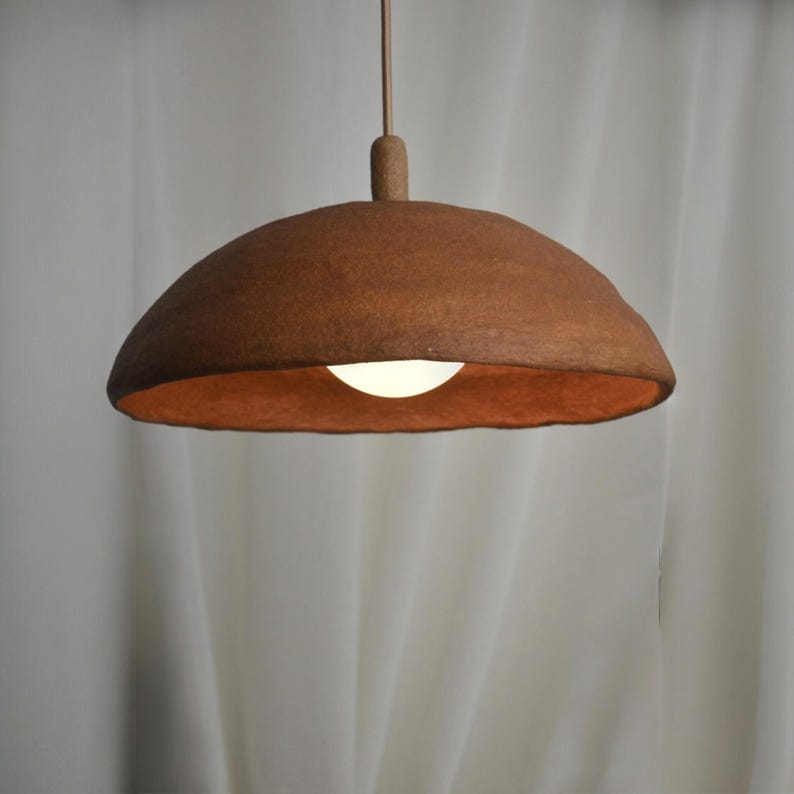 May include: A brown felt pendant light fixture with a white light bulb inside. The light fixture is hanging from a white ceiling.
