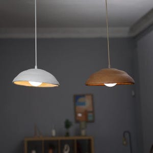 May include: Two hanging pendant lights with white and brown paper shades. The lights are turned on and illuminate the room.
