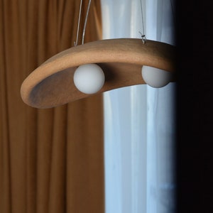 May include: A brown, curved, hanging light fixture with two white globe light bulbs.