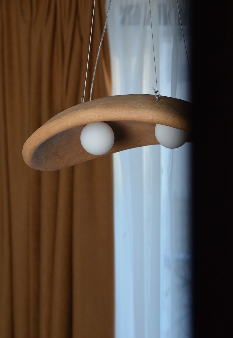 May include: A brown, curved, hanging light fixture with two white globe light bulbs.