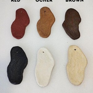 May include: Six irregularly shaped leather samples in different colors: red, ocher, brown, graphite, milk, and beige.