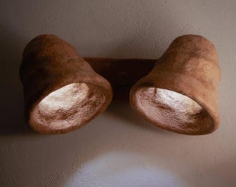 May include: A pair of brown, textured, wall-mounted light fixtures with a rounded, bell-shaped design. The lights are turned on and casting a warm glow.