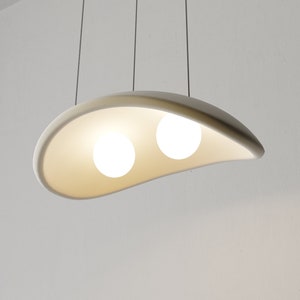 May include: A white ceramic pendant light fixture with two round light bulbs. The fixture is shaped like a curved, elongated oval.