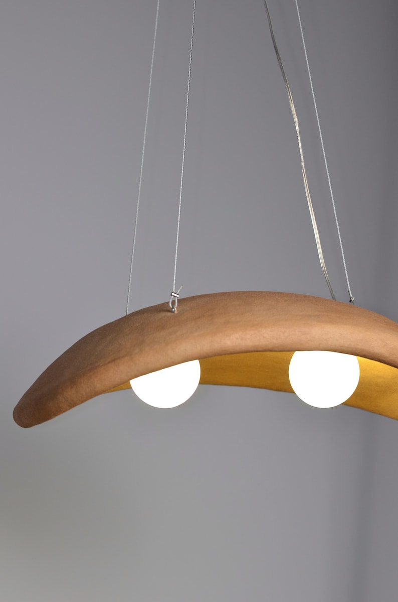 May include: A modern, curved wooden pendant light fixture with two white globe light bulbs.