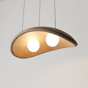 May include: A modern pendant light fixture with a brown, organic-shaped shade and two white globe light bulbs.